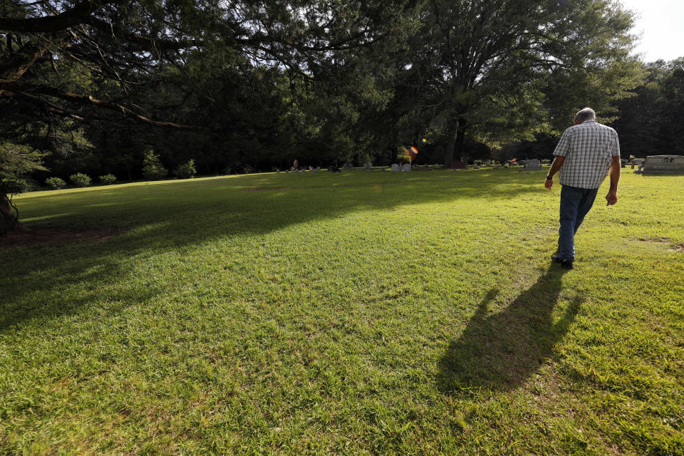 Father Bob Goodyear strolls across the center section of the cemetery on the grounds of the Holy Rosary Indian Mission in Tucker, Miss., Tuesday, July 22, 2020, where about 400 Choctaw are buried in unmarked graves, victims of the 1918 Spanish Flu pandemic. People died so quickly they were buried without markers. The current corona virus has affected the Mississippi Band of Choctaw Indians, leading to an uptake in burials at the cemetery. (AP Photo/Rogelio V. Solis)