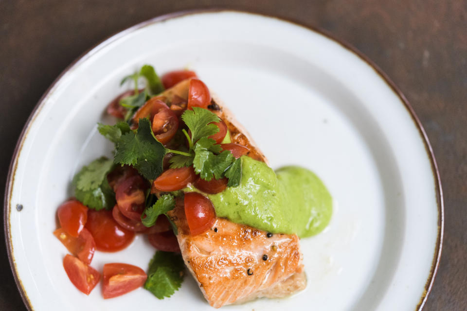 This image released by Milk Street shows a recipe for salmon with avocado sauce and tomato-cilantro salsa. (Milk Street via AP)