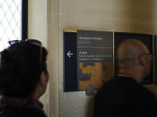 Visiotrs walk past a taped over sign at the Louvre Museum in Paris, France, Wednesday, July 17, 2019. France's Louvre museum has taped over the Sackler name as donors to a wing of the building after protests against the family blamed for the opioid crisis in the United States. (AP Photo/Kamil Zihnioglu)