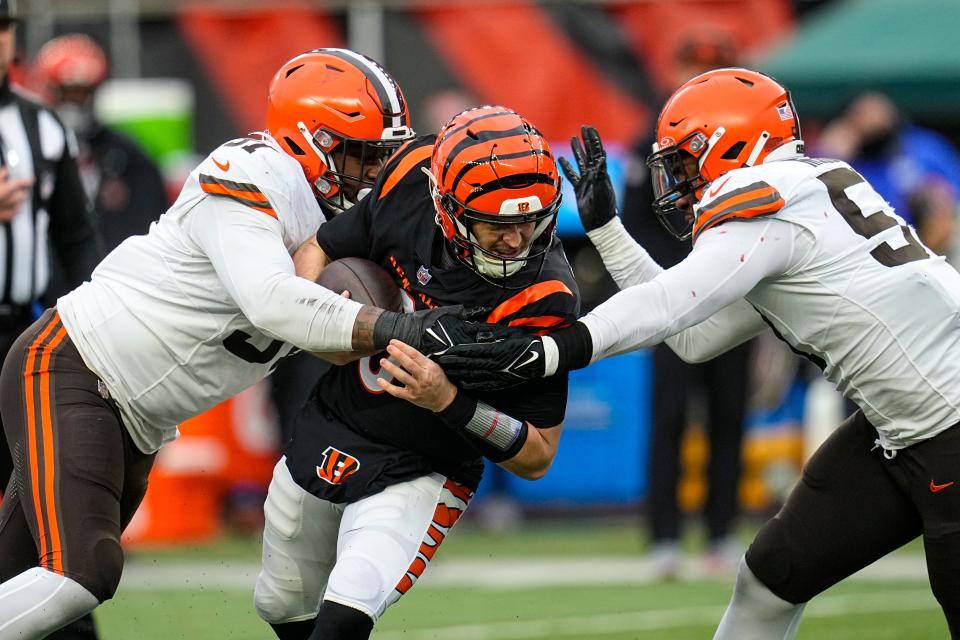 Cincinnati Bengals quarterback Jake Browning (6) is by sacked by Cleveland Browns defensive end Alex Wright (91) and defensive end Isaiah McGuire (57) in the second half Sunday in Cincinnati.