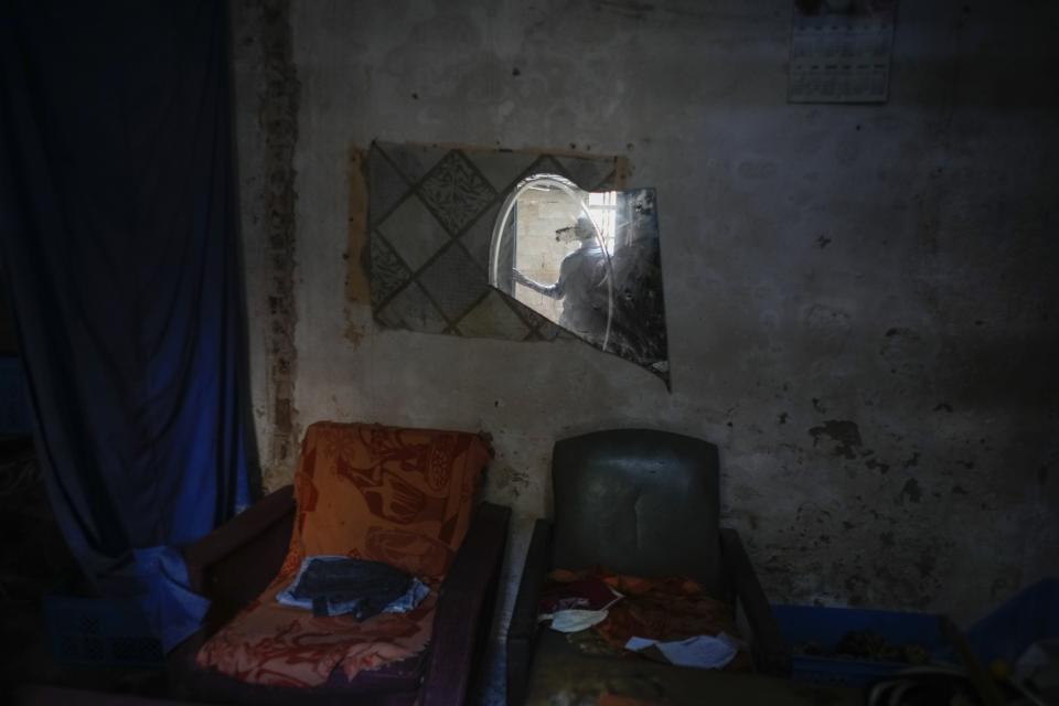 Mario Luis Poll is reflected in a broken mirror inside a dilapidated mansion where he lives with five other families on Villegas Street in Havana, Cuba, Thursday, Oct. 5, 2023. The 57-year-old art restorer who has lived in the building for 19 years has done repairs to try to hold his roof together after the floor of the room above collapsed, saying that the wooden posts that support the roof of the entire construction are almost just for decoration. (AP Photo/Ramon Espinosa)