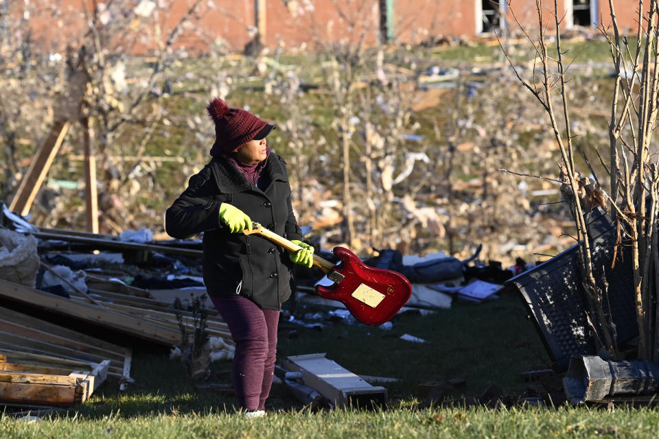 Donna Rogers carries a guitar from the rubble of a destroyed home in the West Creek Farms neighborhood on Sunday, Dec. 10, 2023, Clarksville, Tenn. Central Tennessee residents and emergency workers are continuing the cleanup from severe weekend storms. (AP Photo/Mark Zaleski)