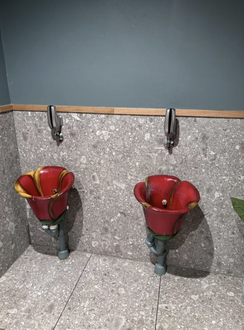 Two unique urinals designed to resemble open red flowers with yellow interiors