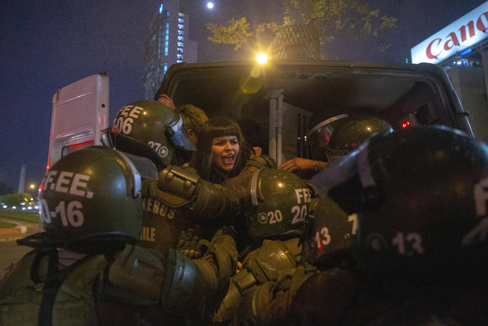 In this Sept. 11, 2019 photo, a woman is detained by police during a feminist protest marking the 46th anniversary of the military coup that ousted the late President Salvador Allende, in Santiago, Chile, Wednesday, Sept. 11, 2019. (AP Photo/Esteban Felix)