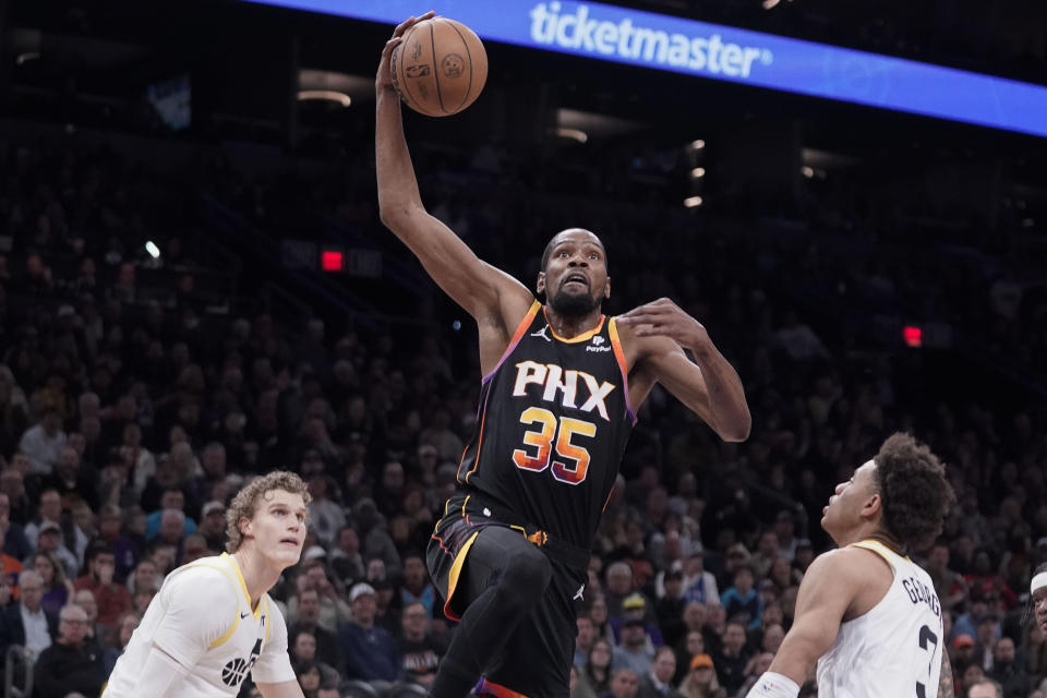 Phoenix Suns' Kevin Durant (35) heads to the basket for a dunk between Utah Jazz's Lauri Markkanen, left and Keyonte George, right, during the second half of an NBA basketball game in Phoenix, Thursday, Jan. 8, 2024. (AP Photo/Darryl Webb)