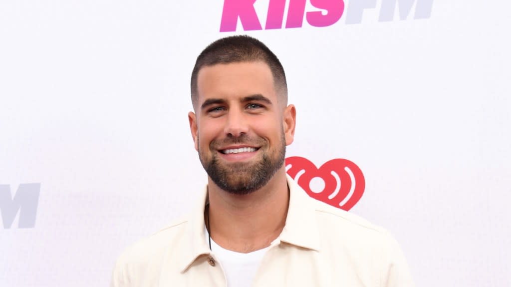 Blake Moynes smiling and posing in a white button up shirt