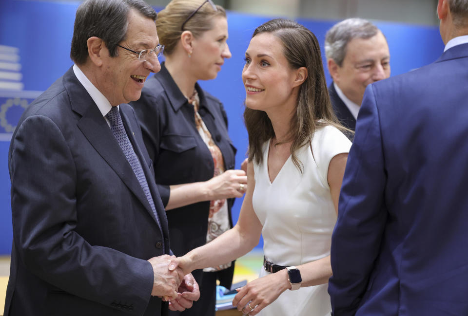 Cypriot President Nicos Anastasiades, left, greets Finland's Prime Minister Sanna Marin, center, during a round table meeting at an EU summit in Brussels, Friday, June 24, 2022. EU leaders were set to discuss economic topics at their summit in Brussels Friday amid inflation, high energy prices and a cost of living crisis. (AP Photo/Olivier Matthys)