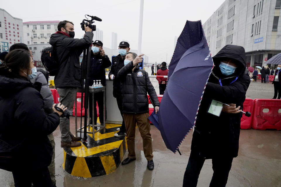 A plainclothes security person uses his umbrella to block journalists after the World Health Organization team arrive at the Baishazhou wholesale market on the third day of field visit in Wuhan in central China's Hubei province on Sunday, Jan. 31, 2021. (AP Photo/Ng Han Guan)