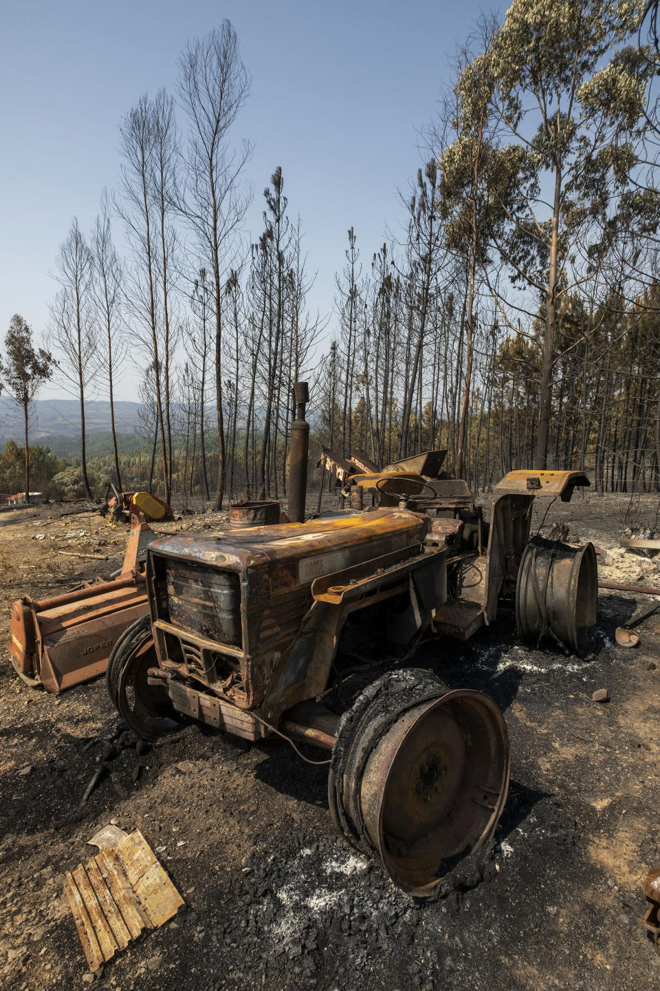 A tractor vehicle is seen burnt following a fire at the village of Roda, near Macao, in central Portugal on Tuesday, July 23, 2019. Emergency services in Portugal have brought under control a huge wildfire which raged for four days and injured 39 people. Civil Protection Agency commander Luis Belo Costa says around 1,000 firefighters are watching out for smoldering hotspots amid temperatures close to 40 degrees Celsius and gusting winds. (AP Photo/Sergio Azenha)