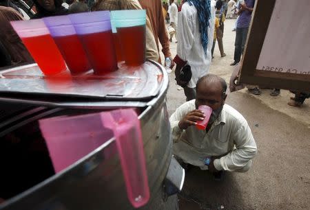 A man squats as he drinks syrup, offered by volunteers (not pictured) in a camp outside Jinnah Postgraduate Medical Centre (JPMC) in Karachi, Pakistan, June 25, 2015. REUTERS/Akhtar Soomro