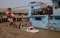 <p>MAR. 17, 2017 – A woman is pulled to safety in a zipline harness in Lima, Peru. Intense rains and mudslides over the past three days have wrought havoc around the Andean nation and caught residents in Lima, a desert city of 10 million where it almost never rains, by surprise. (Photo: Martin Mejia/AP) </p>