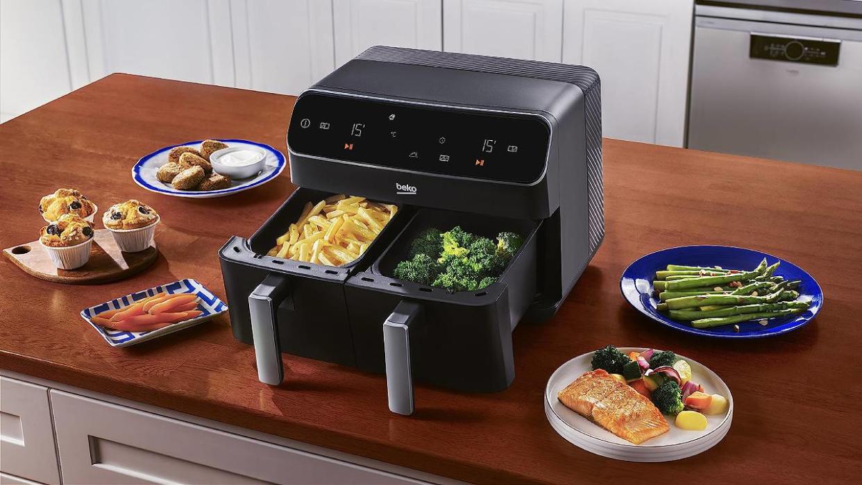  A Beko dual basket air fryer sat on a countertop surrounded by food. 