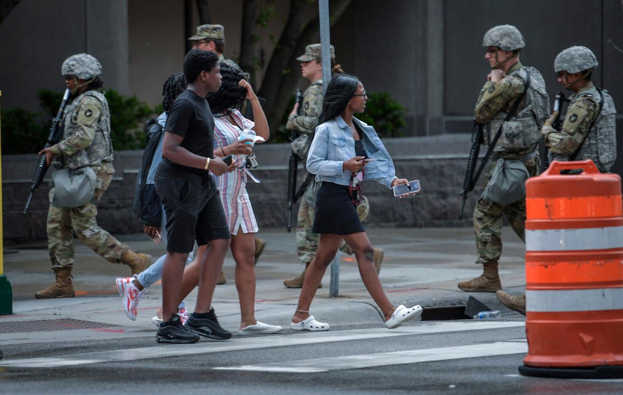 Minnesota National Guard troops walk from the Minneapolis City Hall past pedestrians on Tuesday, June 2, 2020.