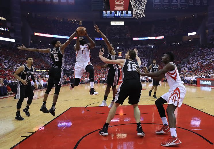 James Harden draws the attention of three Spurs defenders as he drives towards the rim. (Getty)