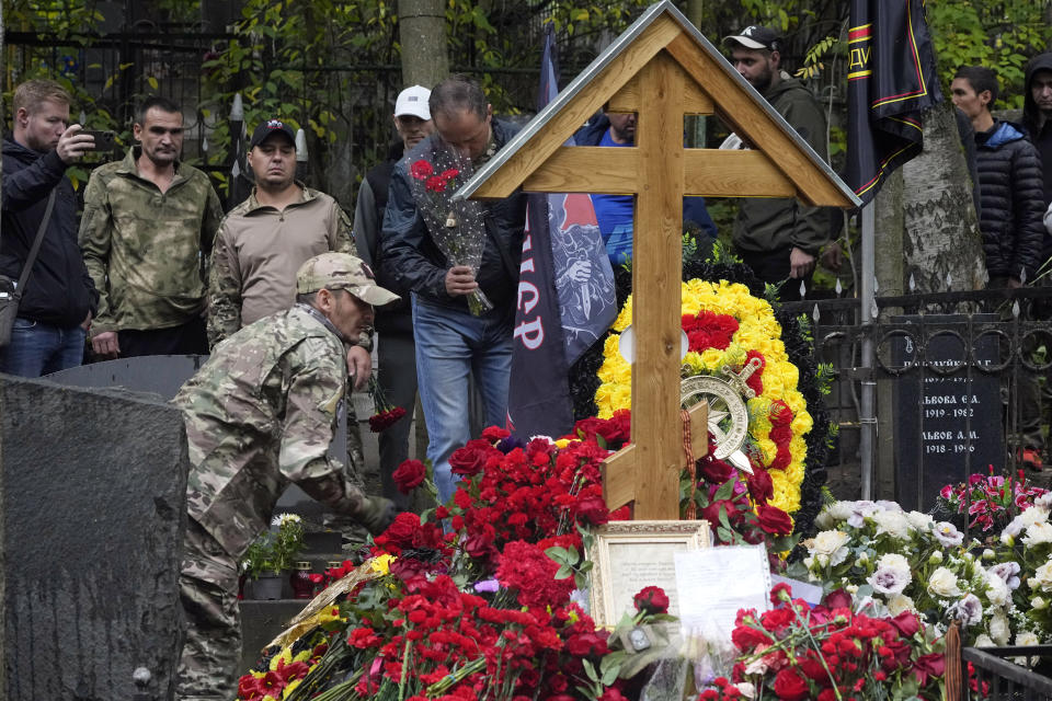 People stand at the grave of Russian mercenary chief Yevgeny Prigozhin who died in a plane crash, marking 40 days from the date of his death, at the Porokhovskoye cemetery in St. Petersburg, Russia, Sunday, Oct. 1, 2023. Prigozhin, the head of the Wagner military contractor, and nine other people, including his top associates, died when his private jet plummeted into a field northwest of Moscow shortly after taking off on Aug. 23. The authorities have remained silent about a possible cause of the crash. (AP Photo/Dmitri Lovetsky)