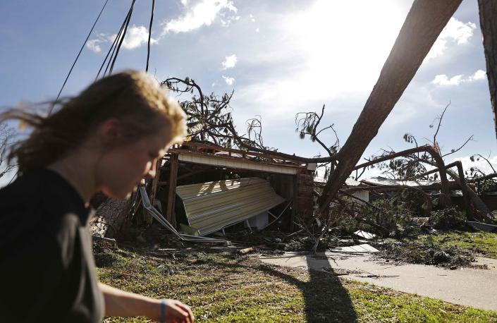 <p>Kelsey Gronbeck walks past damaged homes after checking on a friend’s house in the aftermath of hurricane Michael in Callaway, Fla., Thursday, Oct. 11, 2018. (Photo: David Goldman/AP) </p>