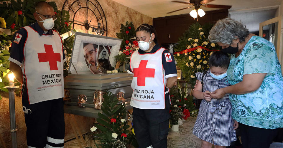 Paramédicos de la Cruz Roja Mexicana y familiares de Juan Andrés García, paramédico de la Cruz Roja y enfermero del IMSS que murió de COVID-19, lloran durante su funeral en Ciudad Juárez, Estado de Chihuahua, Foto de HERIKA MARTINEZ / AFP a través de Getty Images.