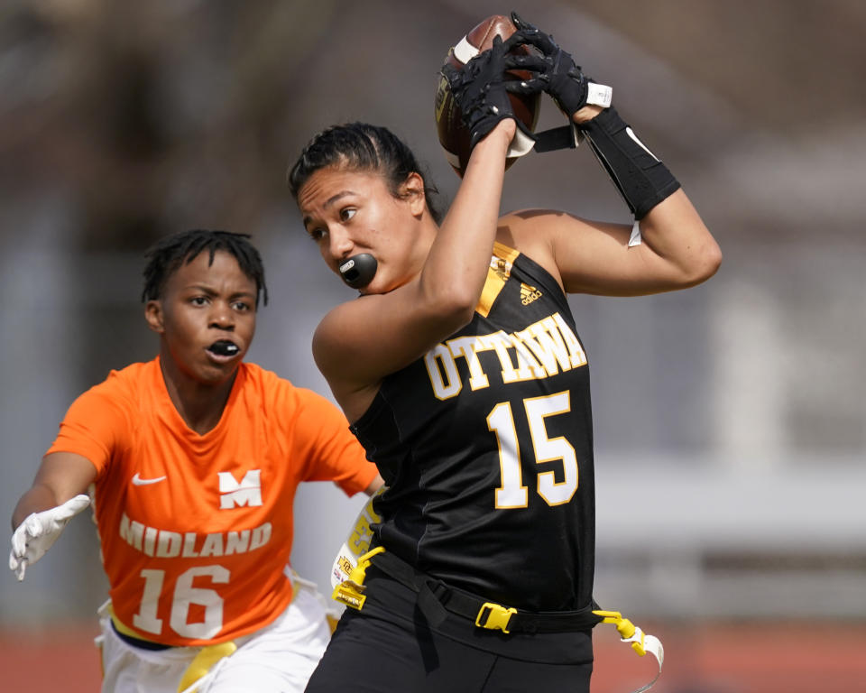 Ottawa receiver Jazlyn Camacho (15) makes a catches while covered by Midland defender E'leseana Patterson (16) during an NAIA flag football game in Ottawa, Kan., Friday, March 26, 2021. The National Association of Intercollegiate Athletics introduced women's flag football as an emerging sport this spring. (AP Photo/Orlin Wagner)