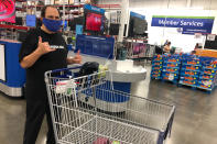 In this Tuesday, March 31, 2020 photo, comedian Frank De Lima poses with a "shaka" gesture while standing in the checkout line at a Sam's Club store in Honolulu. People in Hawaii are changing how they express aloha in the time of coronavirus. Some residents say social distancing is the antithesis of tradition in the state, where people greet each other with hugs, kisses and lei, and families are close-knit. (AP Photo/Jennifer Sinco Kelleher)