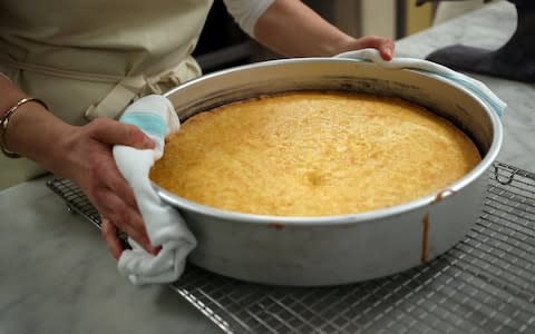 Claire Ptak carries part of the cake out of the oven - Credit: REUTERS/Hannah McKay/Pool 