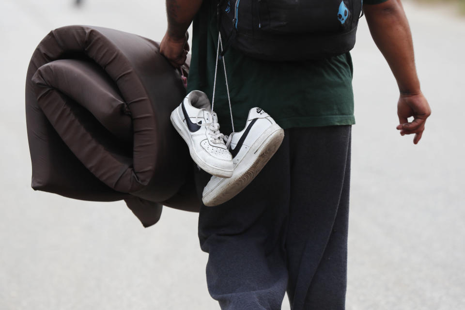 FILE - In this Nov. 3, 2018 file photo, a Central American migrant from the U.S.-bound caravan carries his shoes after a day of walking, in Acayucan, Veracruz state, Mexico. Whenever possible, the migrants discard damaged footwear, replacing them with donated shoes found at stops along the way or with spare pairs they carry in backpacks. (AP Photo/Marco Ugarte, File)