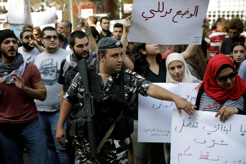 A police officer tries to move protesters back to let cars pass as they demonstrate outside of Lebanon Central Bank during ongoing anti-government protests in Beirut