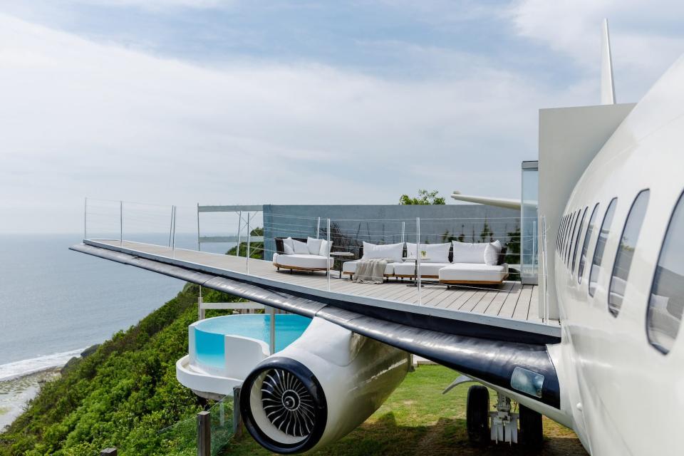 A patio sits atop a plane wing. White furniture sits on the patio.
