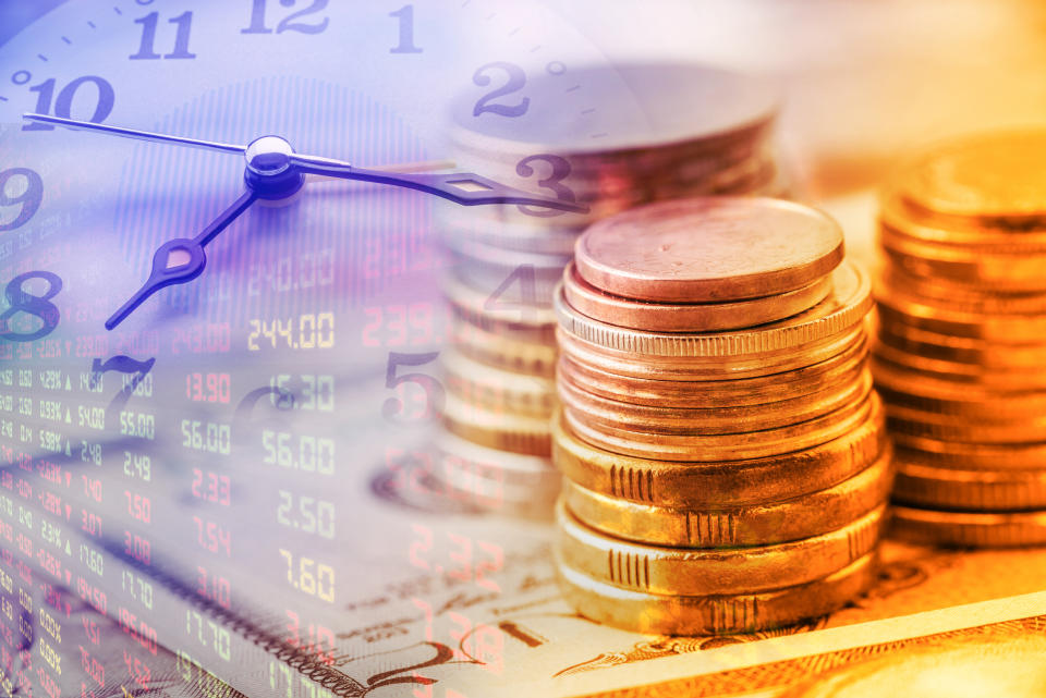 Closeup view : Stack of coins and clock hands. A concept / idea of time value of money. Money at present time is worth more than the same amount in the future due to its potential earning capacity.