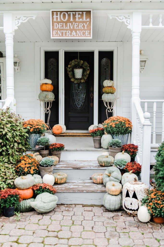 <p>Pumpkins, flowers, and a jack-o'-lantern (made from an old propane tank!) create a classic fall porch display. </p><p><strong>Get the tutorial at <a href="https://www.lizmarieblog.com/2016/09/rustic-fall-farmhouse-steps/" rel="nofollow noopener" target="_blank" data-ylk="slk:Liz Marie Blog;elm:context_link;itc:0;sec:content-canvas" class="link ">Liz Marie Blog</a>.</strong> </p>