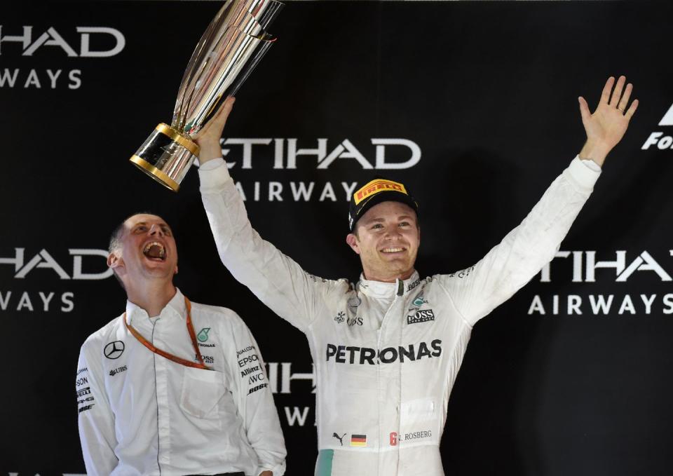 nico rosberg celebrates his formula 1 title in 2016 as he holds up a trophy in his right hand and smiles