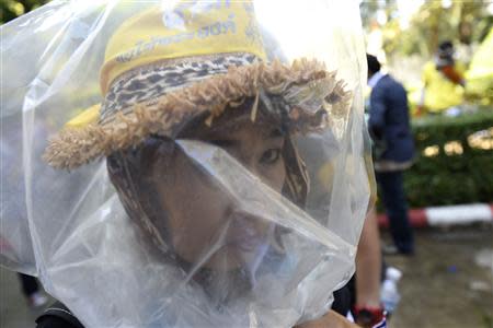 An anti-government protester uses a plastic bag to protect herself from tear gas as they attack Thai riot police at Government House in Bangkok December 1, 2013. REUTERS/Dylan Martinez