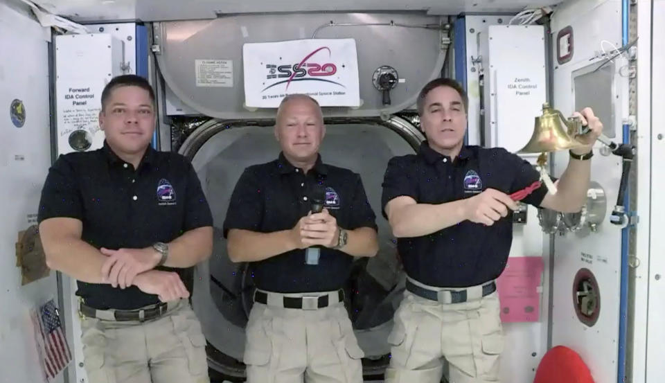 CORRECTS TO NASDAQ, NOT NEW YORK STOCK EXCHANGE - In this image from video made available by NASA, astronaut Chris Cassidy, right, rings the opening bell of the Nasdaq Stock Exchange accompanied by fellow astronauts Robert L. Behnken, left, and Doug Hurley in the International Space Station on Tuesday, June 2, 2020. (NASA via AP)