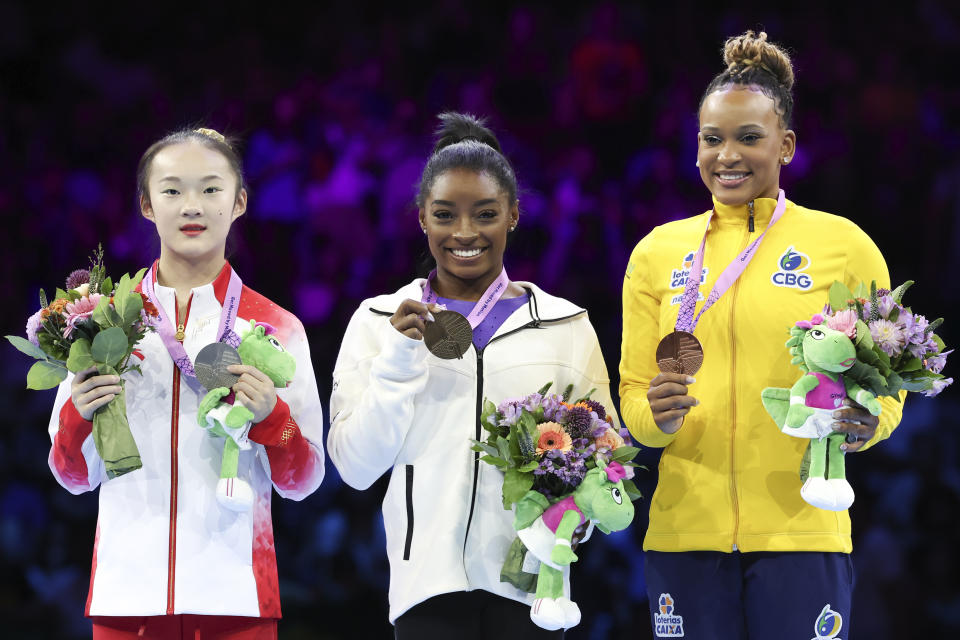 United States' Simone Biles, center and gold medal, China's Zhou Yaqin, left and silver medal, and Brazil's Rebeca Andrade, right and bronze medal, pose on the podium of the beam during the apparatus finals at the Artistic Gymnastics World Championships in Antwerp, Belgium, Sunday, Oct. 8, 2023. (AP Photo/Geert vanden Wijngaert)