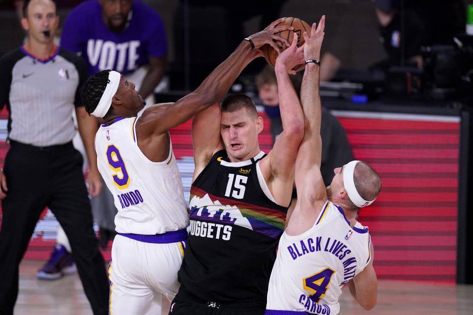 Denver Nuggets' Nikola Jokic (15) struggles to maintain control of the ball under pressure from Los Angeles Lakers' Rajon Rondo (9) and Alex Caruso (4) during the second half of Game 3 of the NBA basketball Western Conference final Tuesday, Sept. 22, 2020, in Lake Buena Vista, Fla. (AP Photo/Mark J. Terrill)