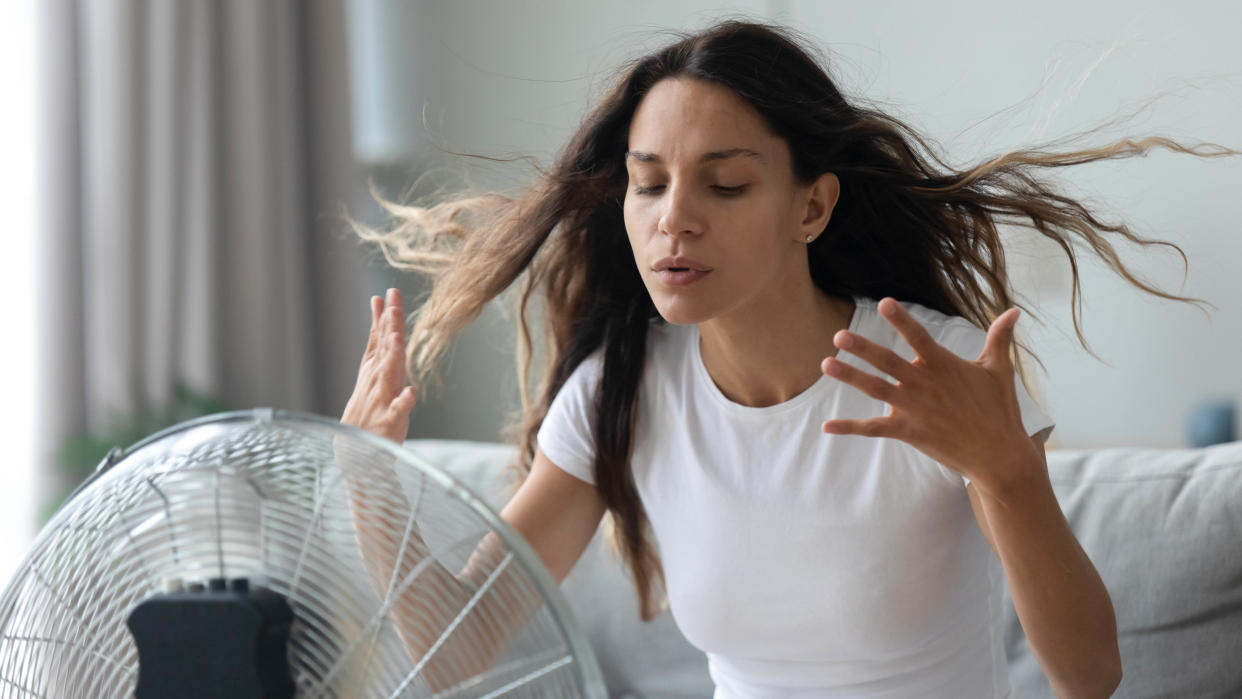  A woman trying to keep cool in front of an electric fan 