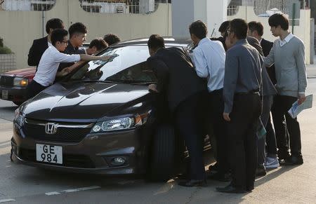 Property sales agents stop a car as they approach a potential client outside a model flat in Hong Kong March 20, 2015. REUTERS/Bobby Yip