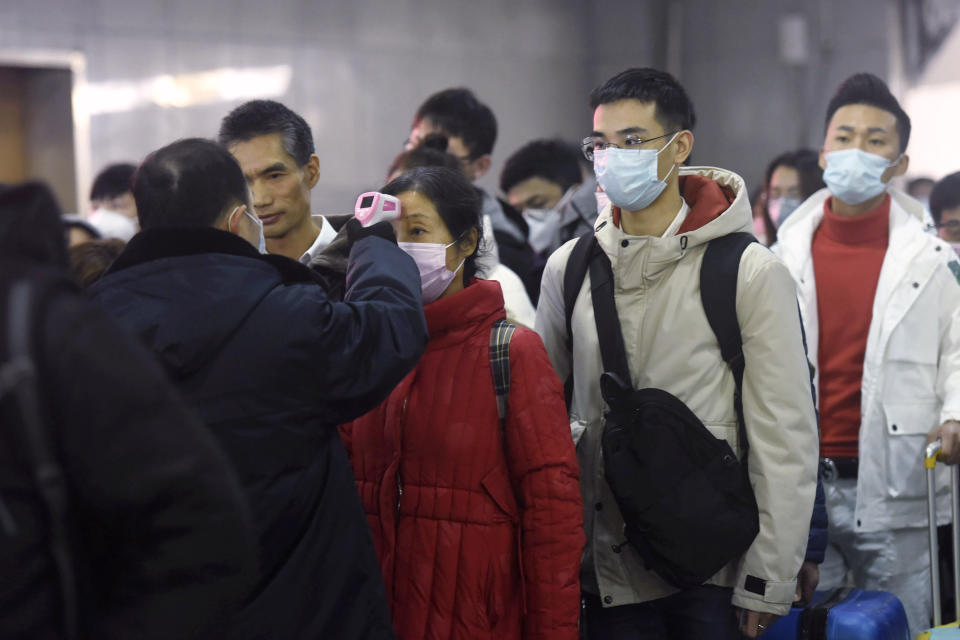 Workers use infrared thermometers to check the temperature of passengers arriving from Wuhan at a train station in Hangzhou in eastern China's Zhejiang Province, Thursday, Jan. 23, 2020. China closed off a city of more than 11 million people Thursday in an unprecedented effort to try to contain a deadly new viral illness that has sickened hundreds and spread to other cities and countries in the Lunar New Year travel rush. (Chinatopix via AP)