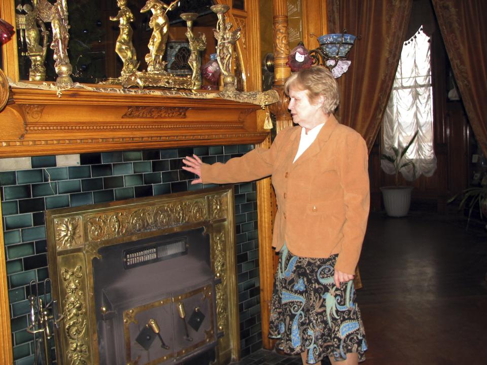 In this photo taken Dec. 24, 2011, Erin Sigl, one of the owners of Copper King Mansion, stands next to a fireplace inside the historic home in Butte, Mont. The 34-room mansion that W.A. Clark built in Butte more than a century ago is now a bed-and-breakfast and offers visitors a glimpse into the pampered lives of the robber barons who ruled American business at the turn of the previous century. (AP Photo/Nicholas K. Geranios)