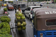 A worker transporting gas canisters pushes his cart against the traffic flow in Jakarta, Indonesia, Tuesday, Jan. 25, 2022. Indonesian parliament last week passed the state capital bill into law, giving green light to President Joko Widodo to start a $34 billion construction project this year to move the country's capital from the traffic-clogged, polluted and rapidly sinking Jakarta on the main island of Java to jungle-clad Borneo island amid public skepticism. (AP Photo/Dita Alangkara)
