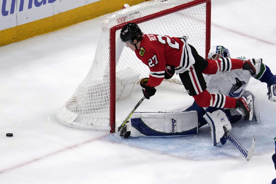 Chicago Blackhawks left wing Lukas Reichel (27) jumps as he reaches for the puck against Vancouver Canucks goaltender Collin Delia, right, during the third period of an NHL hockey game in Chicago, Sunday, March 26, 2023. (AP Photo/Nam Y. Huh)