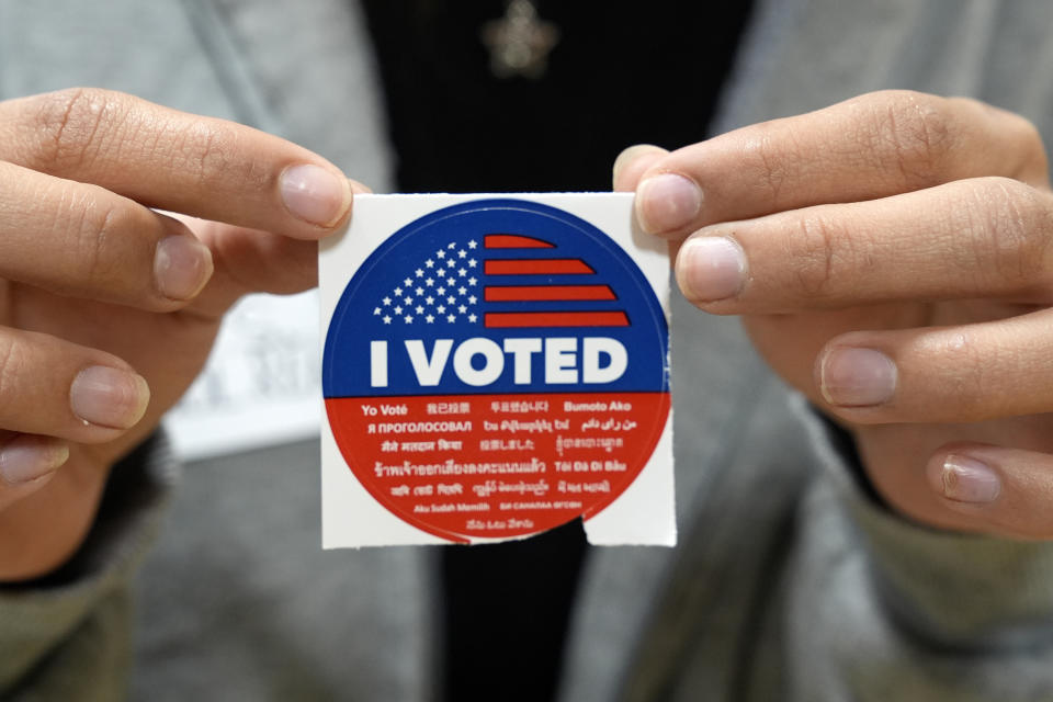 A election volunteer offers voters an "I Voted" sticker after casting their ballot on Super Tuesday, at the Ranchito Elementary School polling station in the Panorama City section of Los Angeles, Tuesday, March 5, 2024. Super Tuesday elections are being held in 16 states and one territory. Hundreds of delegates are at stake, the biggest haul for either party on a single day. (AP Photo/Richard Vogel)