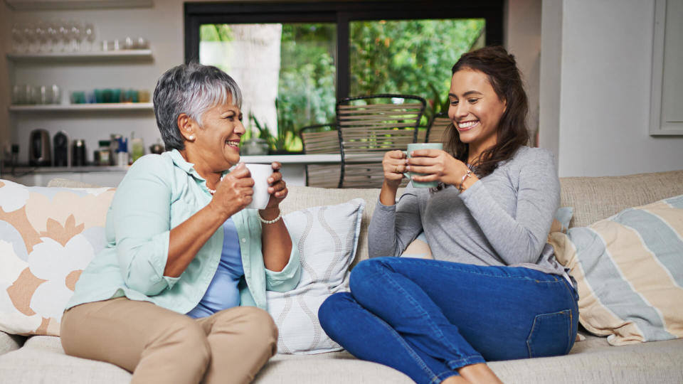 young woman and her mother chatting on the sofa while drinking coffee