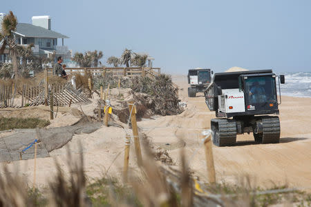 Residents look on as tracked vehicles haul sand to replenish the heavily eroded shoreline at Flagler Beach, Florida, U.S., January 26, 2018. Picture taken January 26, 2018. REUTERS/Gregg Newton