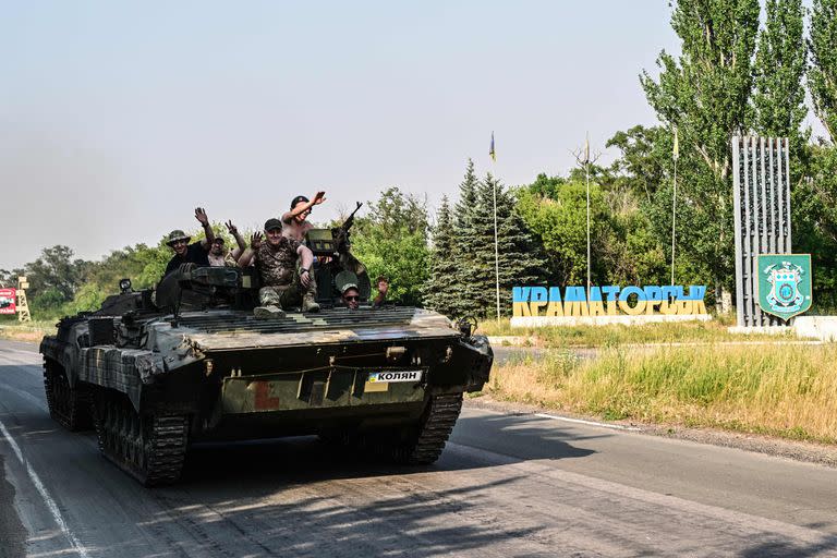 Ukrainian soldiers on the top of a Ukrainian armoured fighting vehicle gesture as they drive down at the exit of Kramatorsk, eastern Ukraine, on July 6, 2022, amid the Russian invasion of Ukraine. (Photo by MIGUEL MEDINA / AFP)
