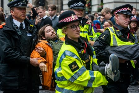 Police officers remove a volunteer with the Extinction Rebellion in London