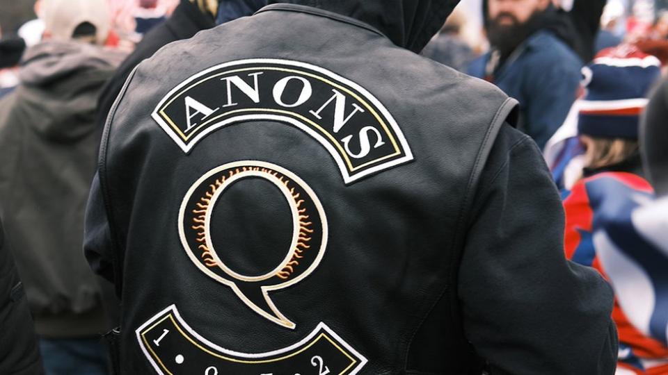 Persona fotografiada desde atrás con chaqueta QAnon