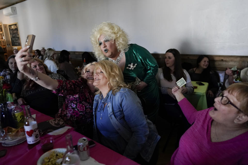 La drag queen Alexus Daniels, vestida como Dolly Parton, posa para selfies con miembros de la audiencia mientras actúa en "Spring Fever Drag Brunch", el domingo 26 de marzo de 2023, en Kulpmont Winery en Kulpmont, Pensilvania. (Foto AP/Carolyn Kaster)