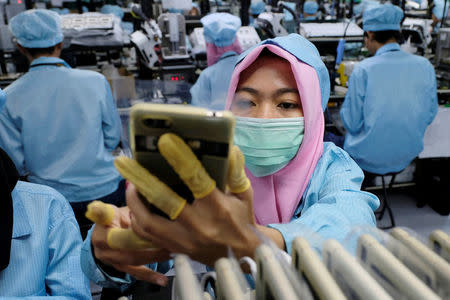 A worker holds an OPPO F1S smartphone at the OPPO smartphone factory in Tangerang, Indonesia, September 20, 2016. REUTERS/Beawiharta