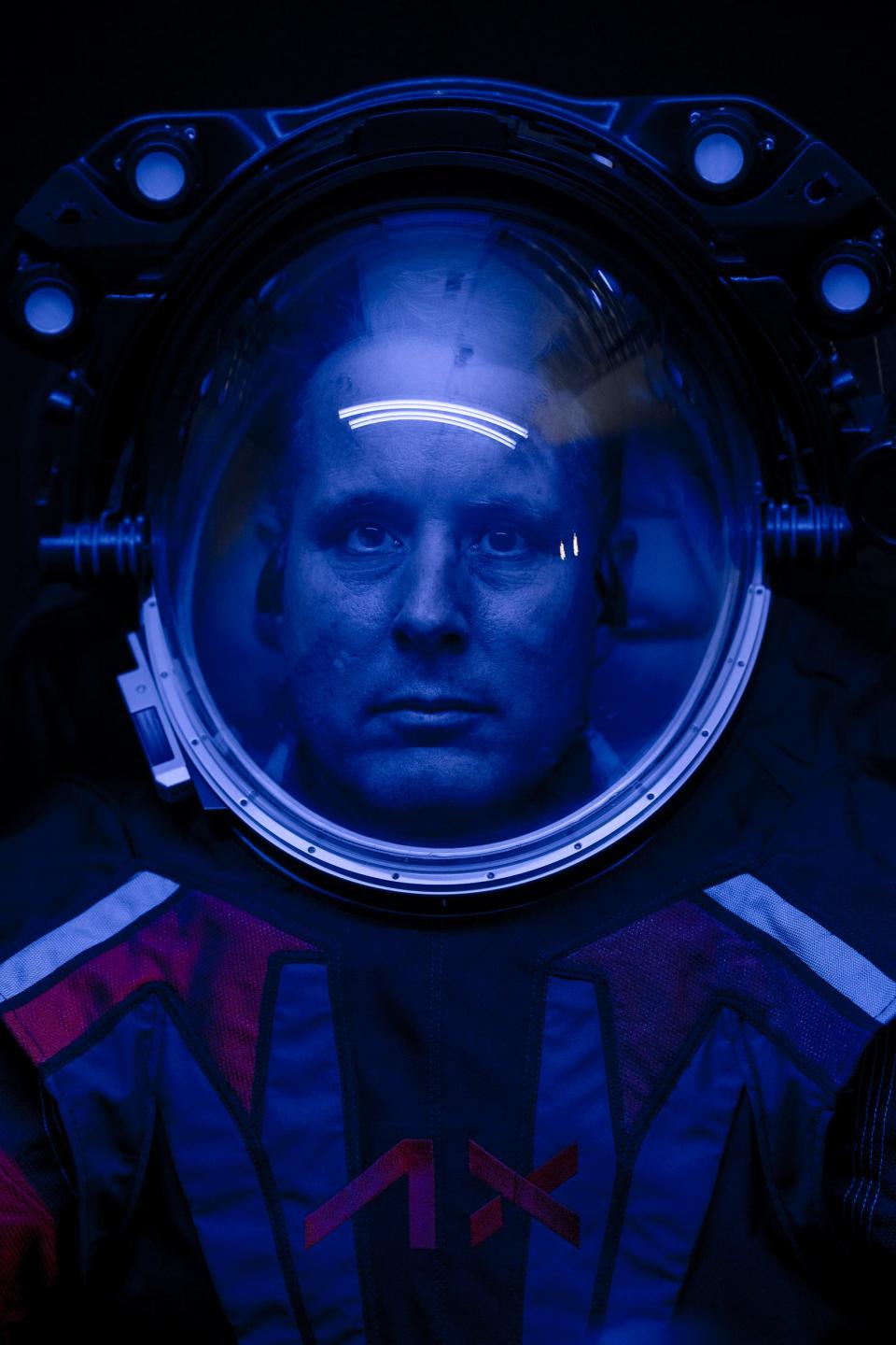 man in spacesuit helmet in dark blue light