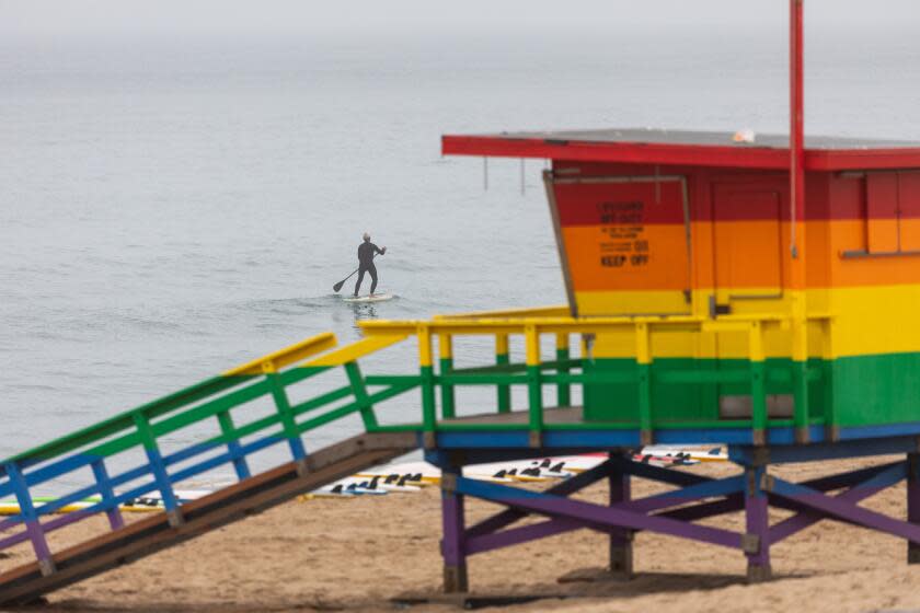 Hermosa Beach, CA - July 03: A paddleboarder is seen on a foggy morning in the waves off Hermosa Beach, CA, Monday, July 3, 2023. On the day before Independence Day, the south bay of Los Angeles is socked-in with clouds. (Jay L. Clendenin / Los Angeles Times)